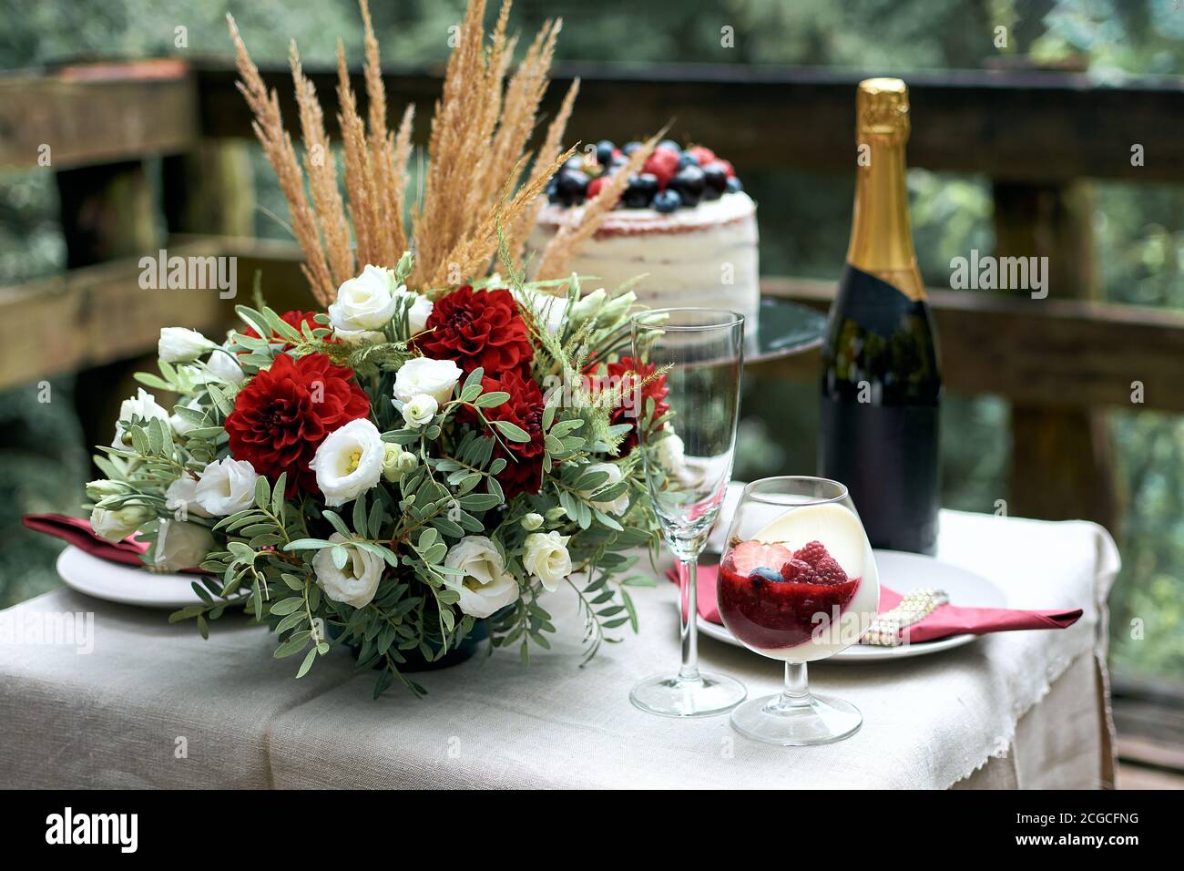 Festlicher Tisch für ein romantisches Date. Zusammensetzung von frischen Blumen. Sommer nackte Kuchen mit Beeren. Leichte cremige Dessert mit Erdbeeren, Himbeeren a Stockfoto