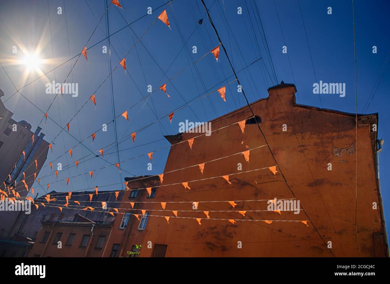 Orangefarbene Urlaubsfahnen leuchten in der Sonne vor dem Hintergrund Von alten Häusern und blauen Himmel Stockfoto