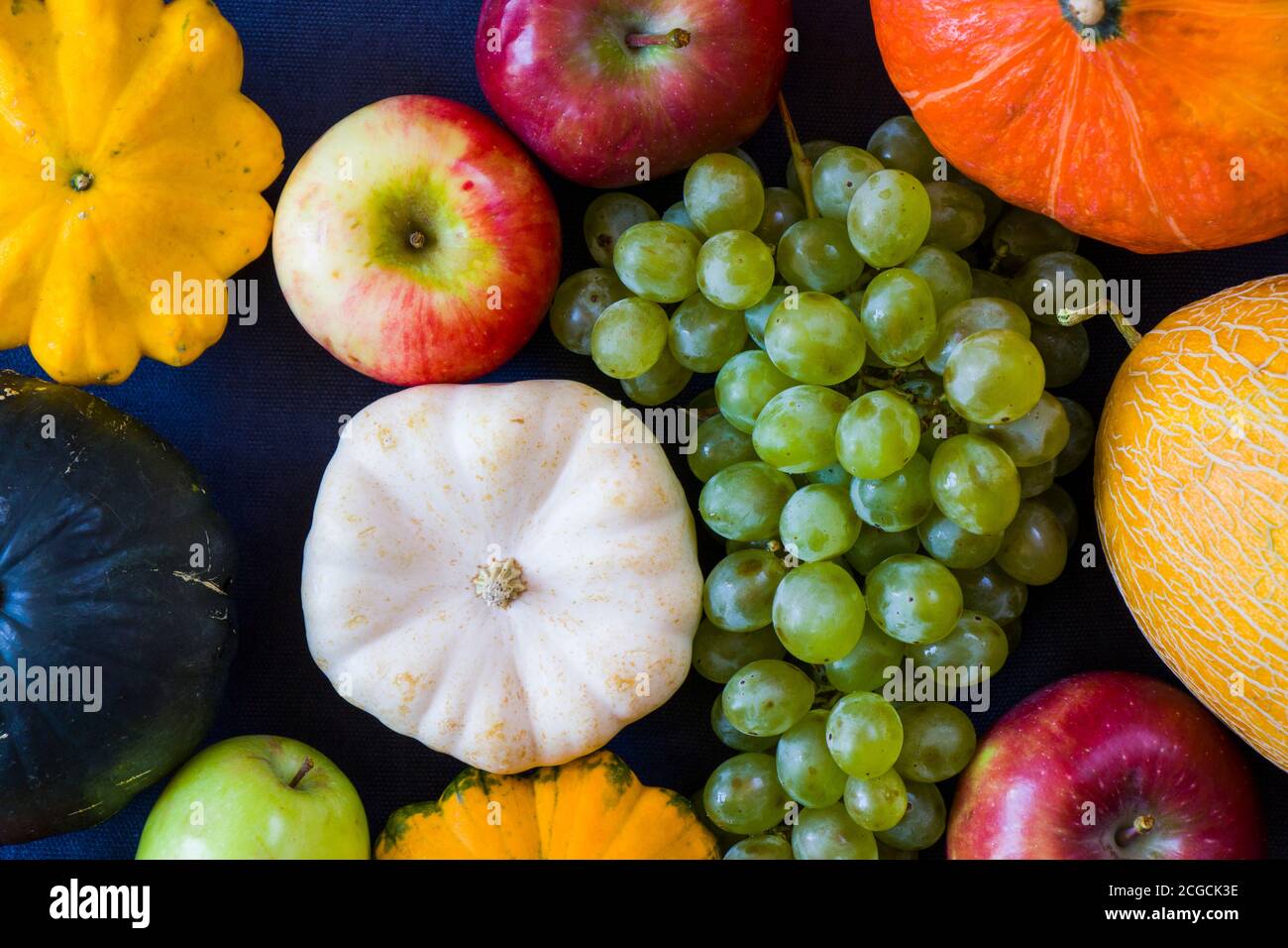 Herbst- und Herbsternte, Kürbis, Apfel, Traube und pattison auf blauem Hintergrund Stockfoto