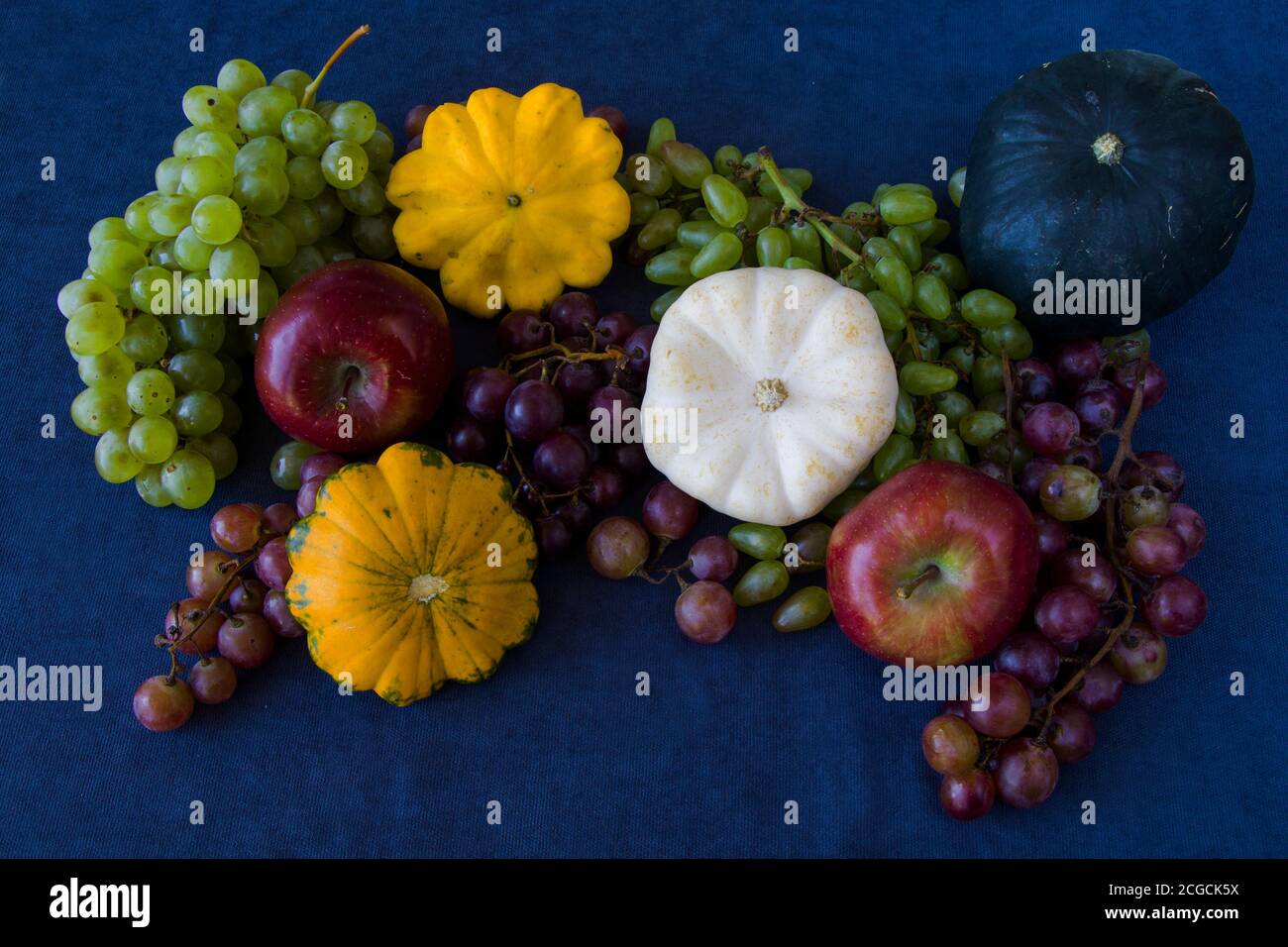 Herbst- und Herbsternte, Kürbis, Apfel, Traube und pattison auf blauem Hintergrund Stockfoto