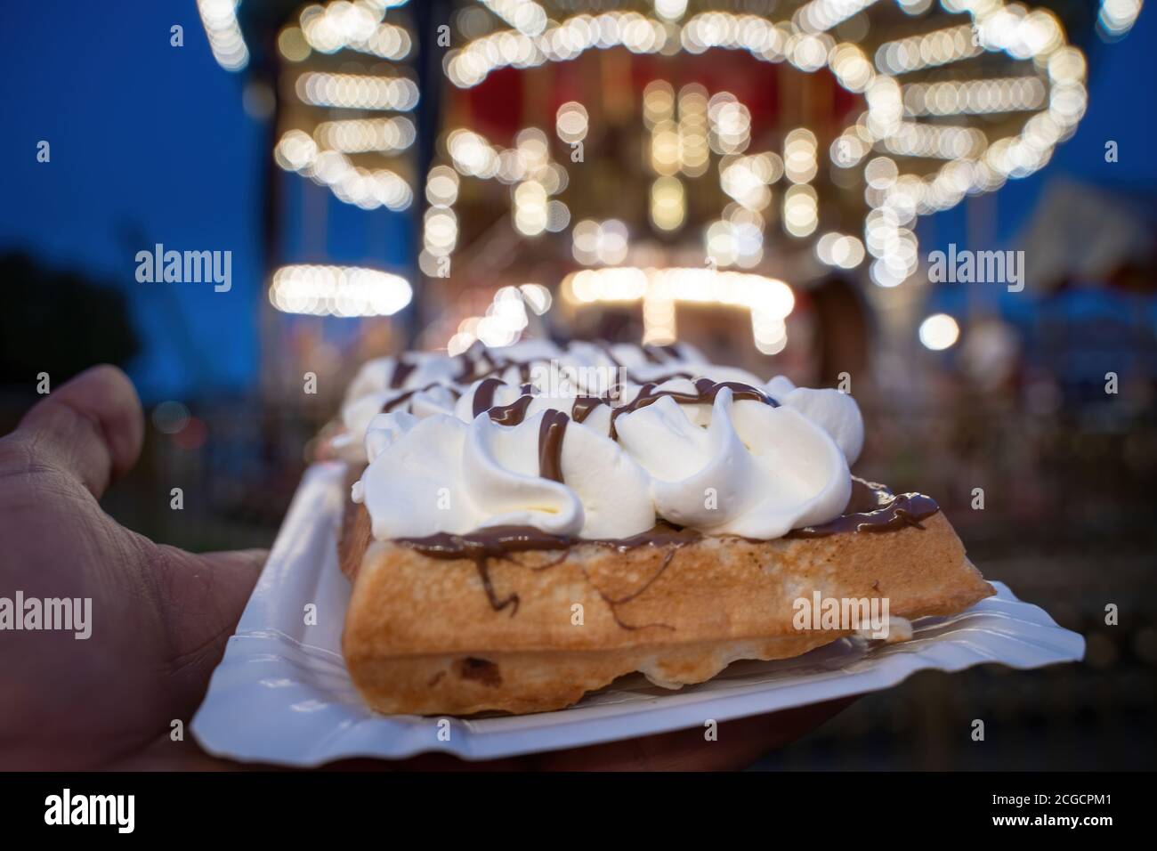 Nahaufnahme der berühmten Waffel unter Touristen in der Stadt Zentrum Altstadt gegen beleuchtete Karussell für Kinder in der Hintergrund Stockfoto