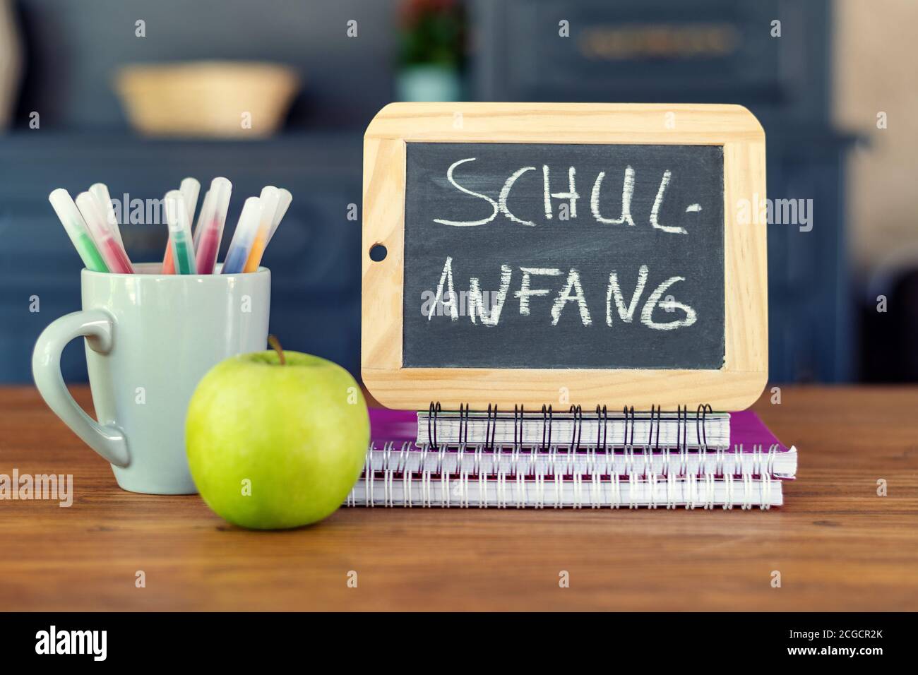 Zurück zur Schule. Konzept mit Kugelschreibern, Büchern, einem Apfel und einer Tafel mit Aufschrift : Zurück zur Schule Stockfoto