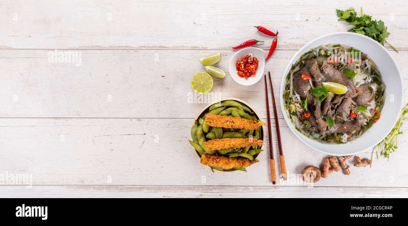 Draufsicht Zusammensetzung von Pho bo und Vorspeise mit gebratenen Garnelen. Asiatische Lebensmittel in Schüsseln, freier Platz für Text Stockfoto