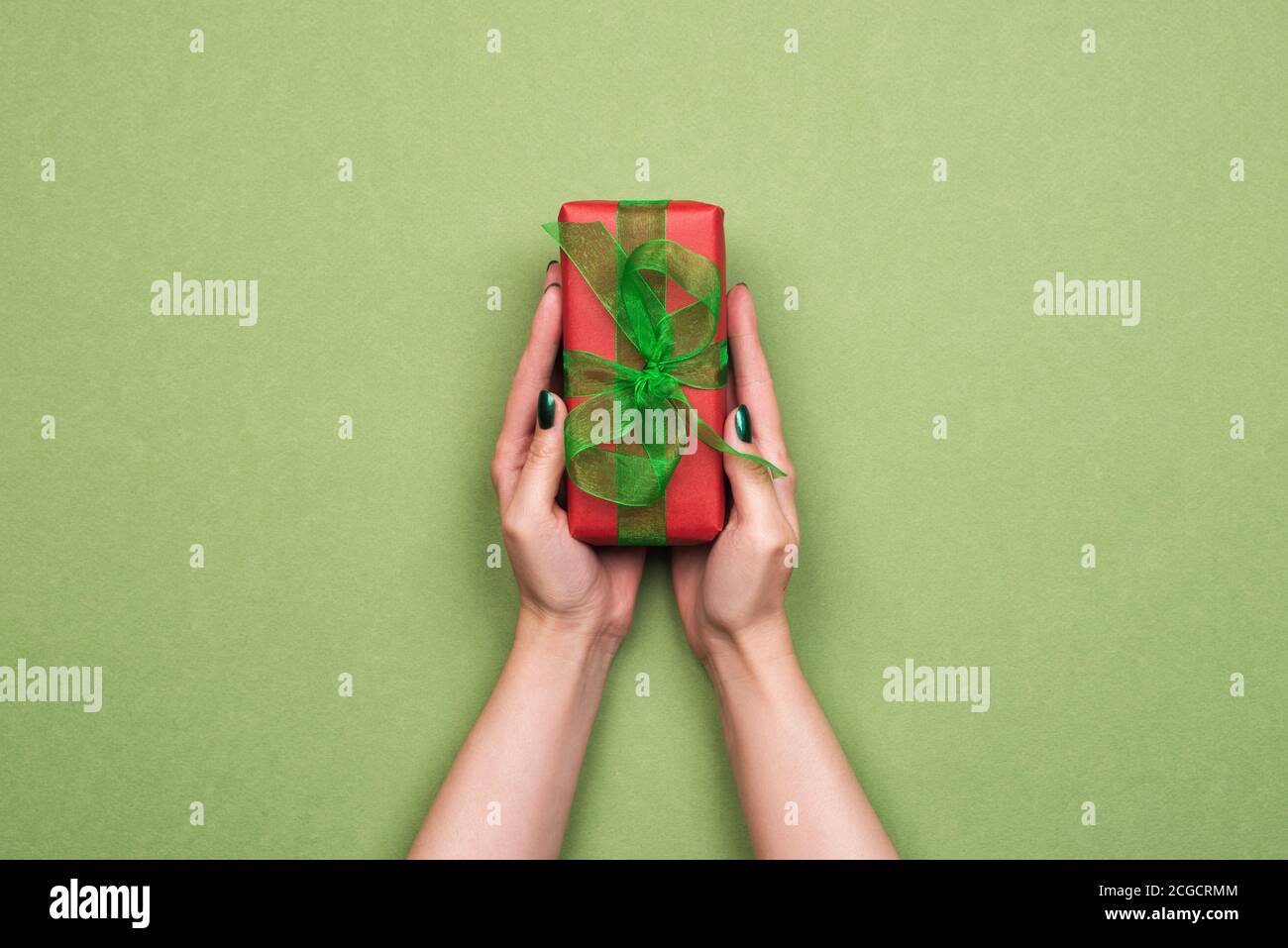 Weibliche Hände halten Geschenk in rotem Papier verpackt Stockfoto