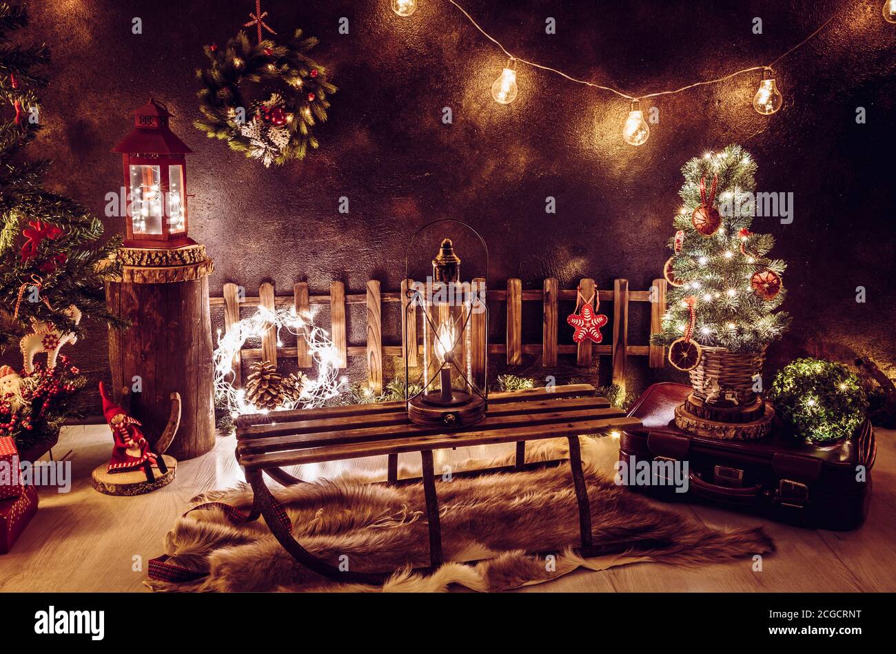Weihnachtsthema Arrangement im dunklen Abend Heim Zimmer. Viele Party-String Lichter beleuchtet, Laternen, alte Retro-Schlitten, winzigen Weihnachtsbaum. Stockfoto