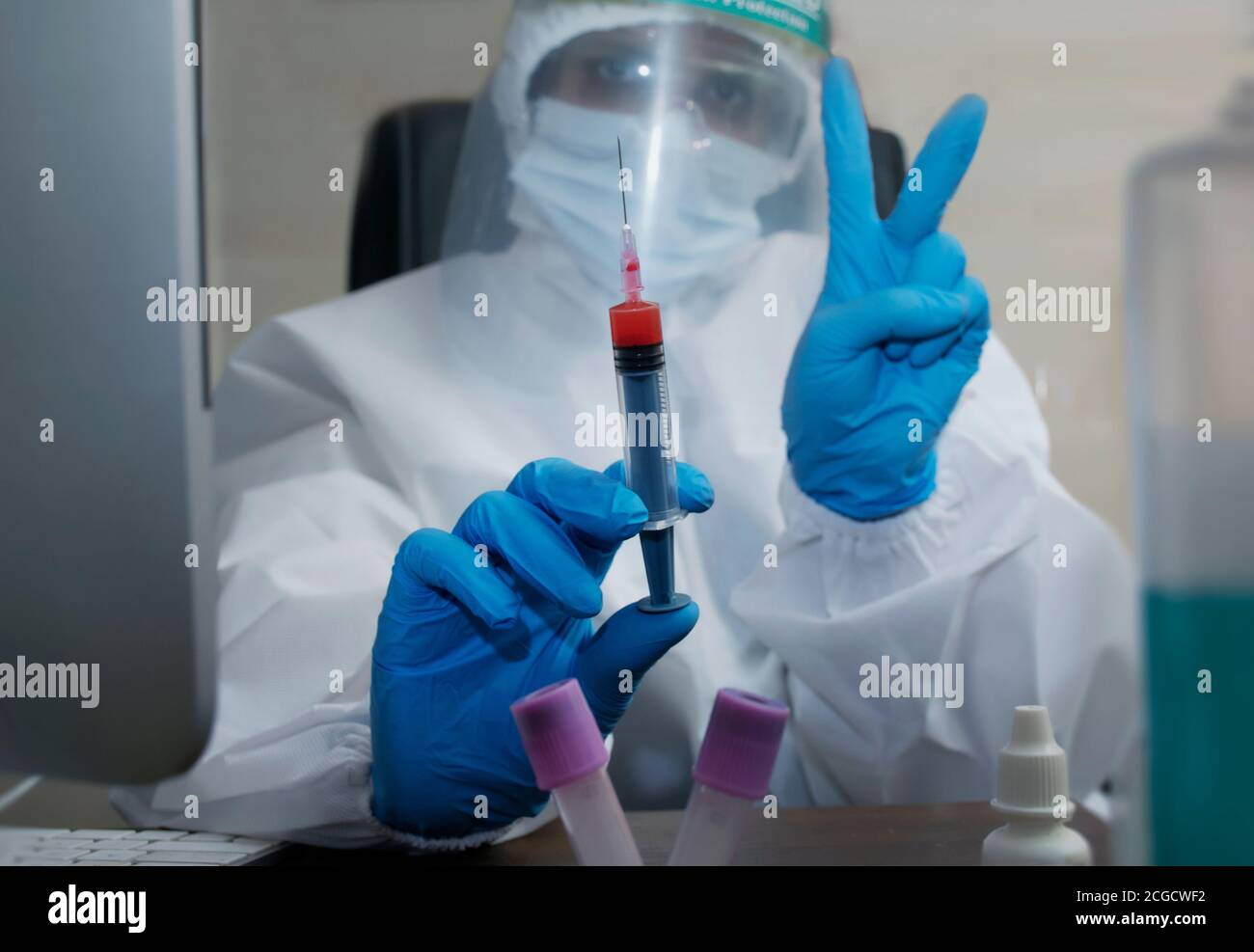 Ärztin Krankenschwester hält Coronavirus-Impfstoff und zeigt Siegeszeichen Stockfoto