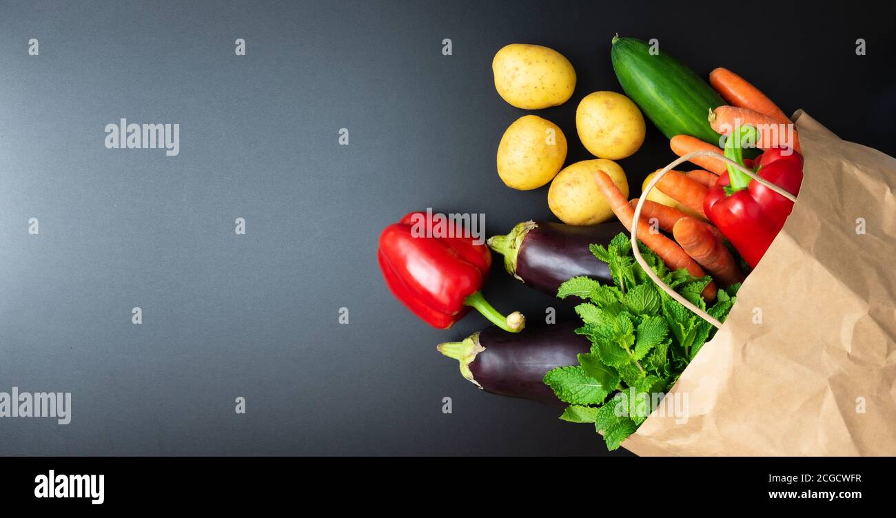 Oben Blick auf frisches Bio-Gemüse aus Papier Einkaufstasche auf dunkle Küchentheke verschüttet, gesunde Ernährung und Kochkonzept Stockfoto