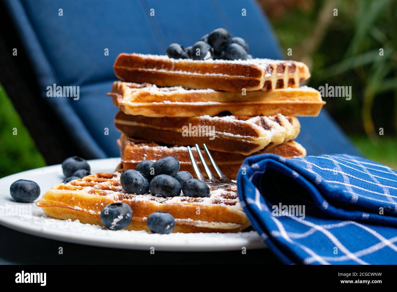 Original belgische Waffeln gerade gebacken und als Stapel serviert Mit frischen Heidelbeeren auf einem weißen Teller draußen Stockfoto