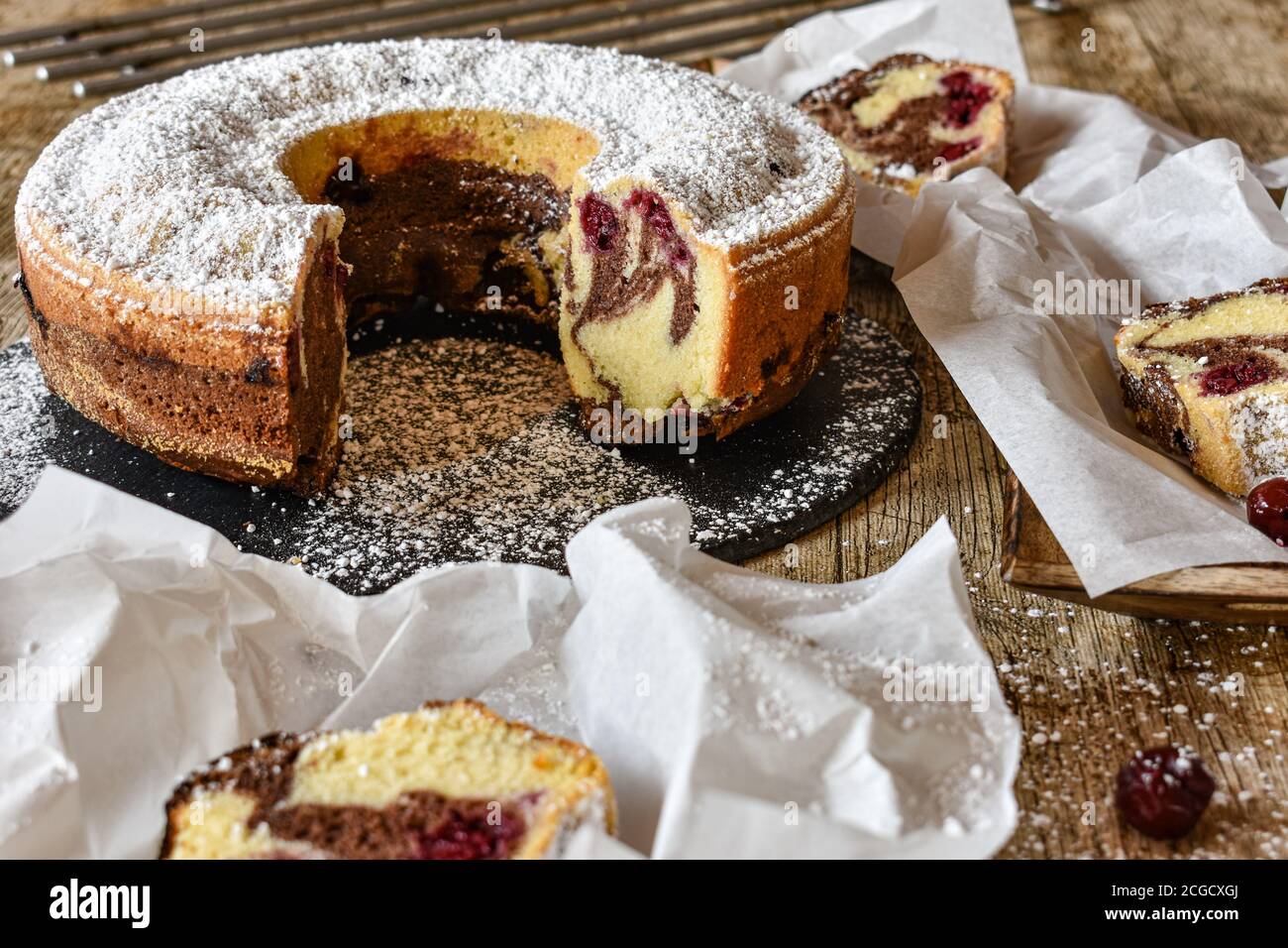 bunt Marmor fröhliche Kuchen auf einem schwarzen Teller serviert Ein Holztisch - frisch und hausgemacht - bereit zu Essen Stockfoto
