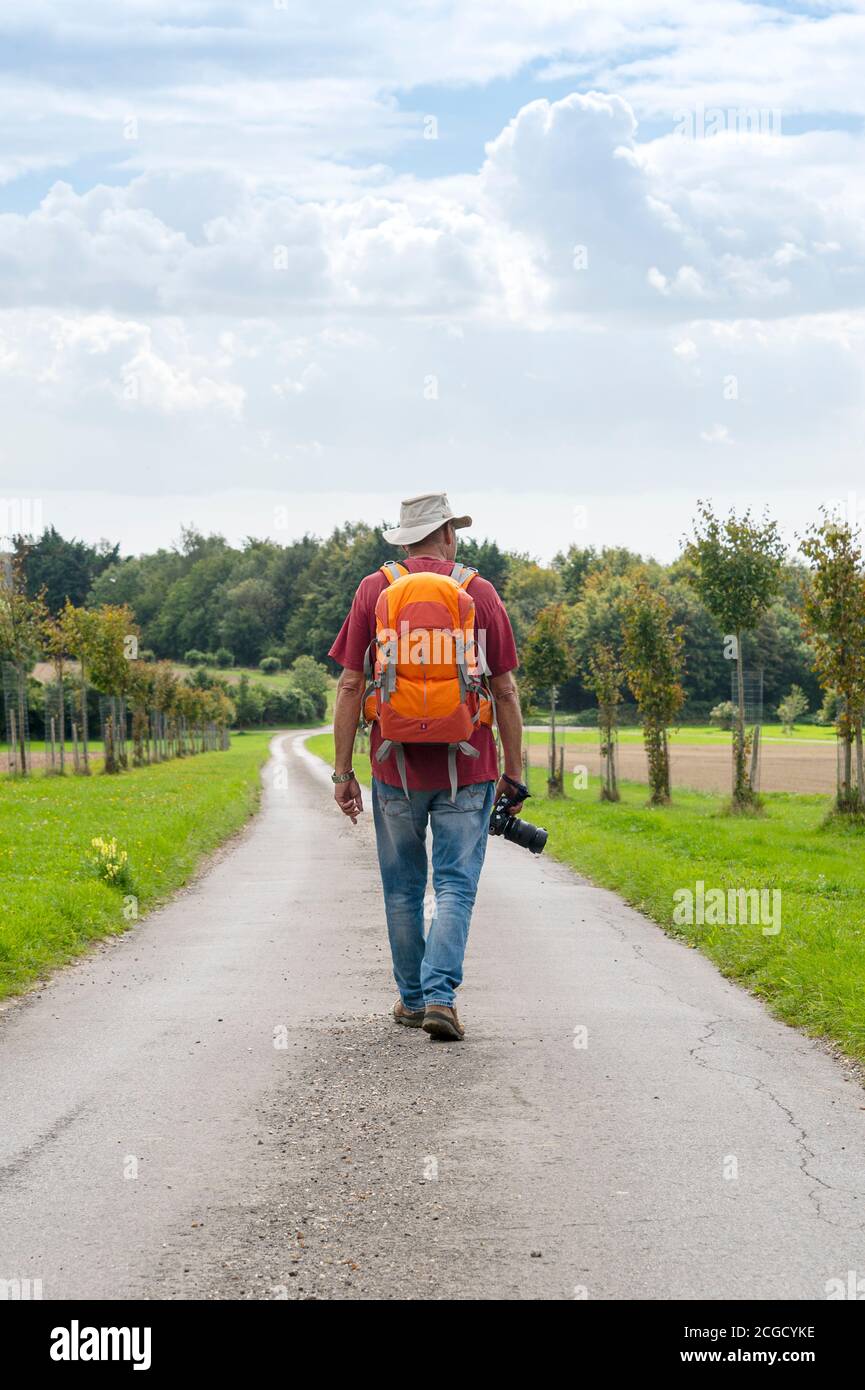 Rückansicht eines reifen Mannes, der mit einem Rucksack läuft Und eine Kamera halten Stockfoto