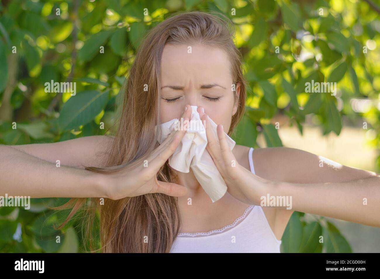 Sommer im Garten. Junge Frau bläst ihre Nase wegen Pollenallergie. Stockfoto