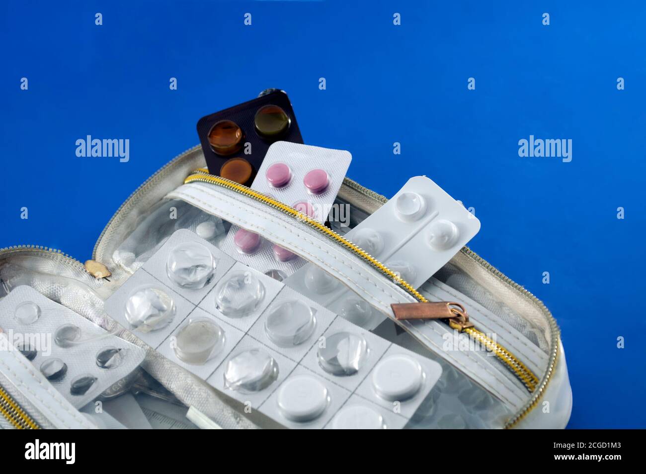 Weiße Handtasche, mit halbleeren Tablettblasen auf blauem Hintergrund, Stockfoto