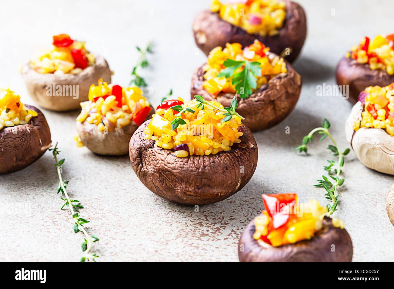 Gefüllte portobello-Pilze mit Bulgur, Gemüse und aromatischen Kräutern auf betontem Hintergrund. Vegetarisches Essen. Stockfoto