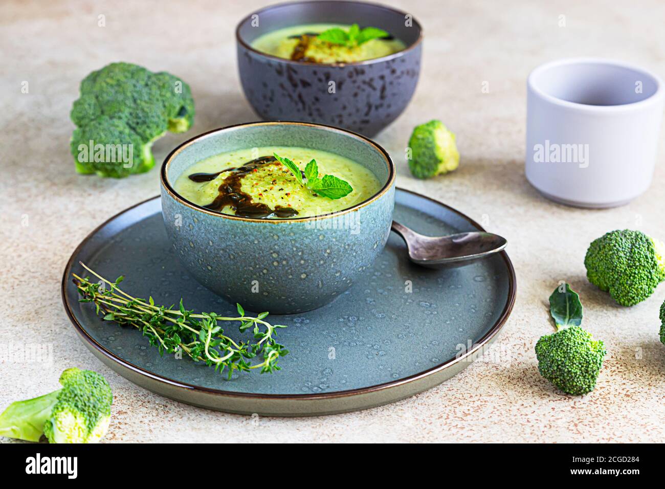 Brokkoli oder grüne Spinatsuppe mit aromatischem würzigem Öl in einer Schüssel. Vegan gesundes Essen. Steinhintergrund. Stockfoto