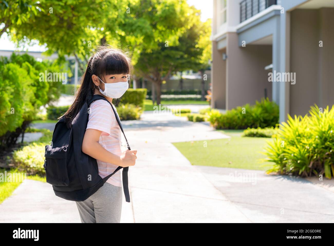 Porträt von niedlichen asiatischen Grundschule Mädchen in medizinische Maske vor zu Hause während COVID-19 Pandemie. Die morgendliche Schulroutine für den Tag im Leben g Stockfoto