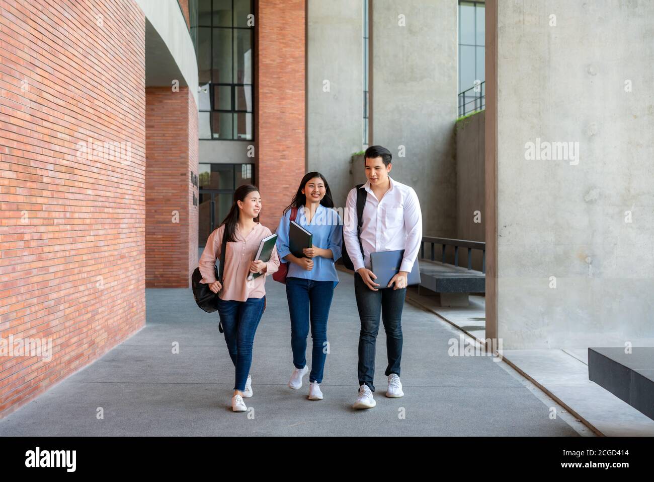 Drei asiatische Studenten gehen in der Universitätshalle während der Pause an der Universität zu Fuß und reden zusammen. Bildung, Lernen, Student, Campus, Universität, Stockfoto