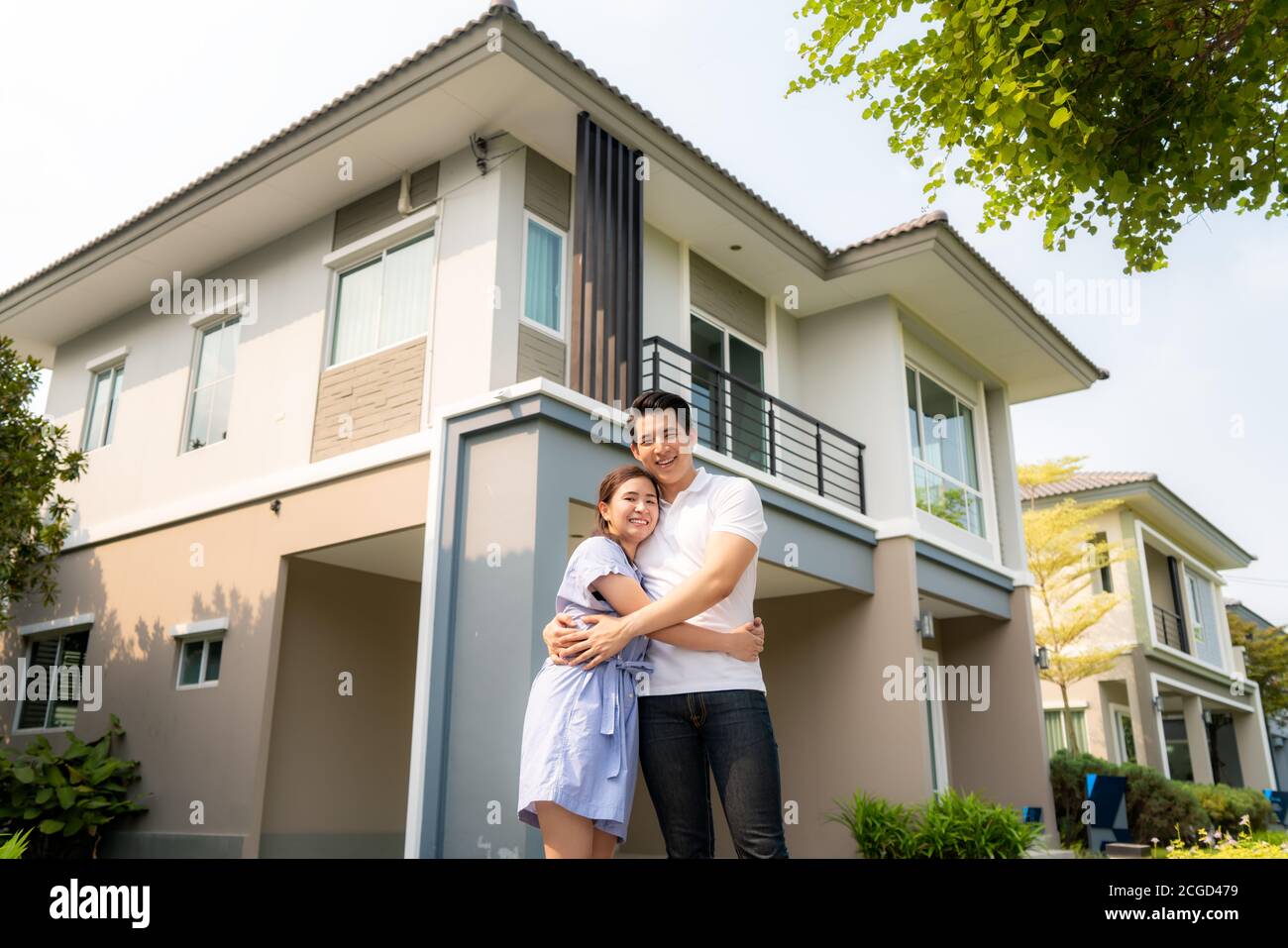 Porträt des jungen asiatischen Paares, das zusammen steht und umarmt und vor ihrem neuen Haus glücklich aussieht, um neues Leben zu beginnen. Familie, Alter, Zuhause, echte Esta Stockfoto