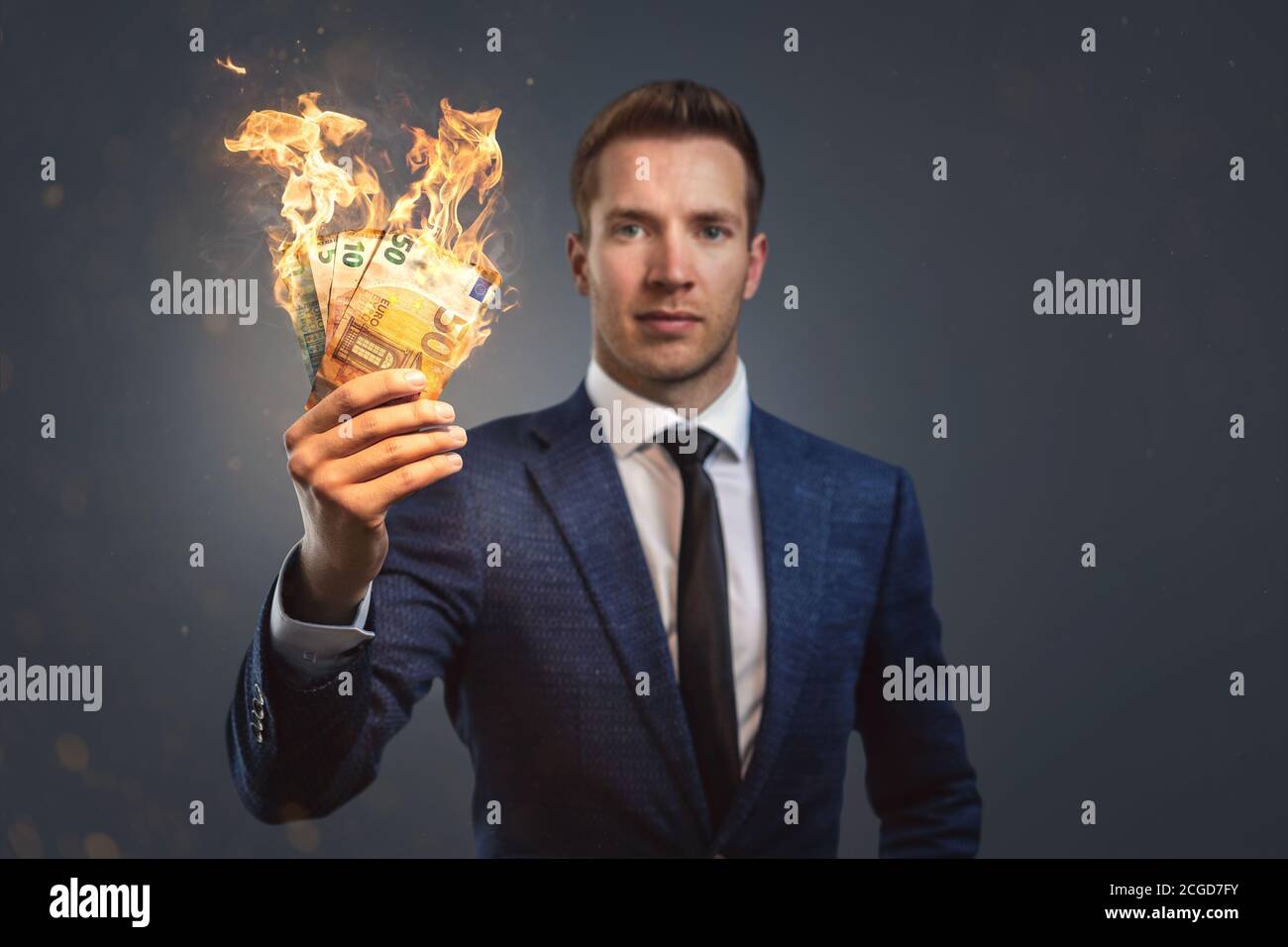 Geschäftsmann hält brennendes Geld in der Hand Stockfoto