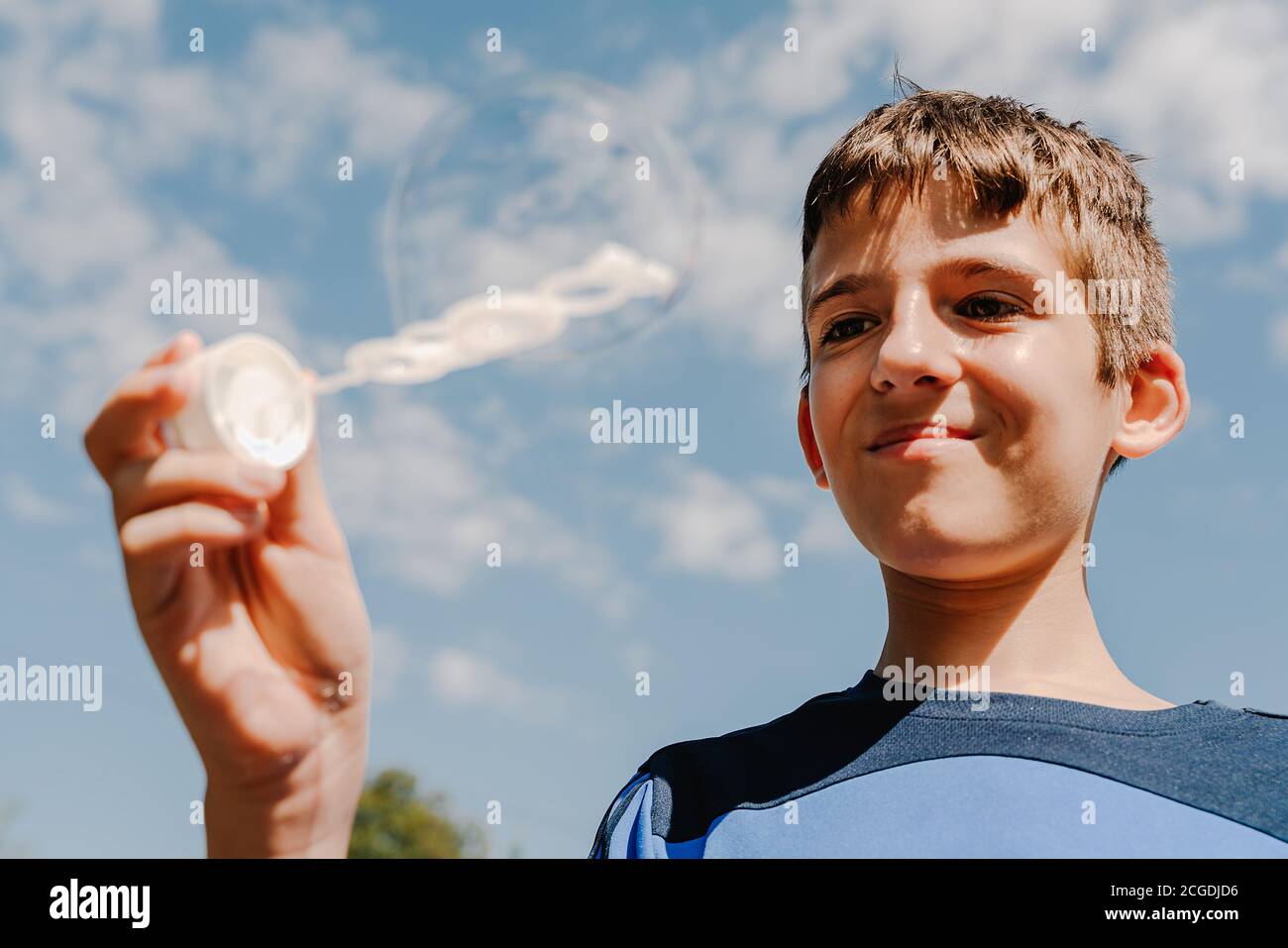 Junge weiße Junge suchen eine Seifenblase im Freien mit Himmel Im Hintergrund Stockfoto