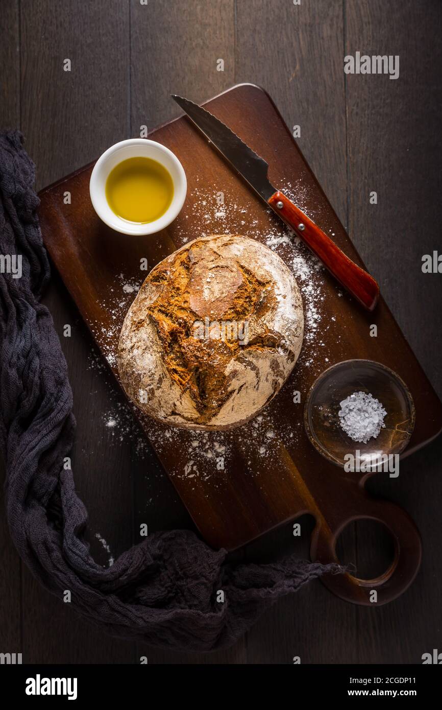 Frisch gebackenes Brot auf Schneidebrett mit Salz und Olivenöl. Draufsicht. Stockfoto