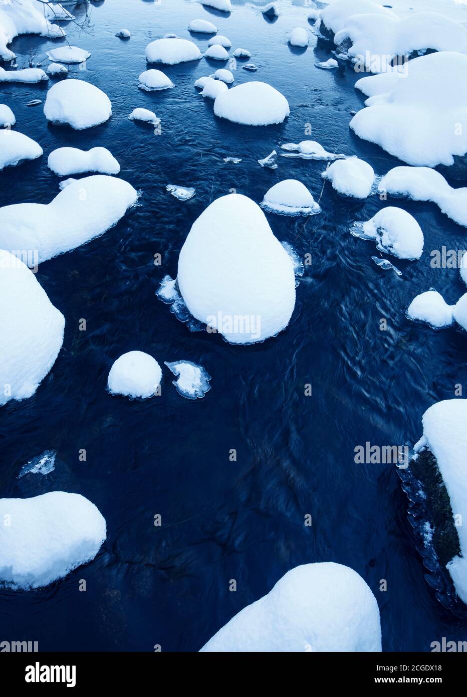 Verschneite Steine auf kleinen Bach im Winter, Finnland Stockfoto