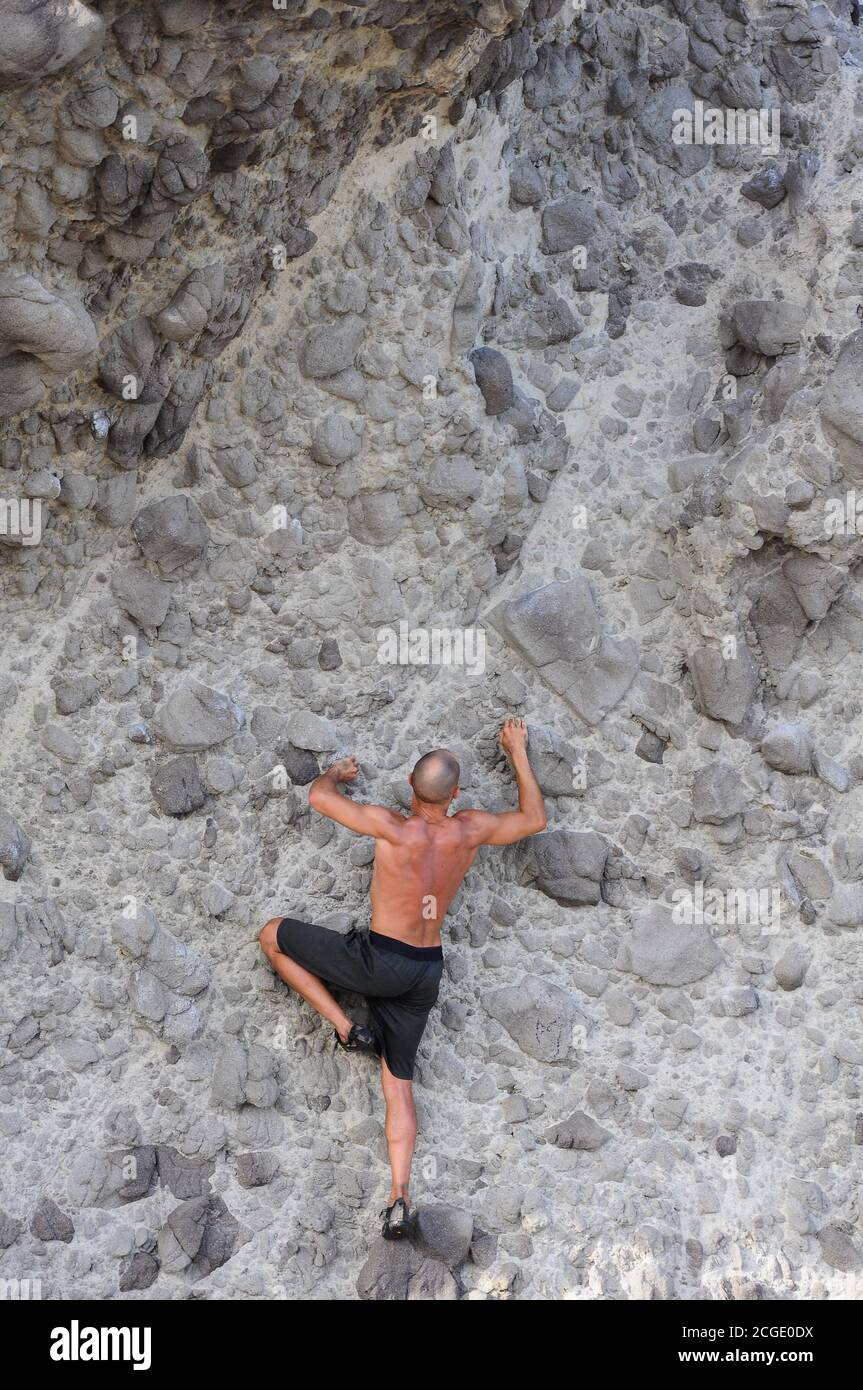 Mann klettert eine vertikale Klippe ohne Sicherheitsmaßnahmen, Extremsport Stockfoto