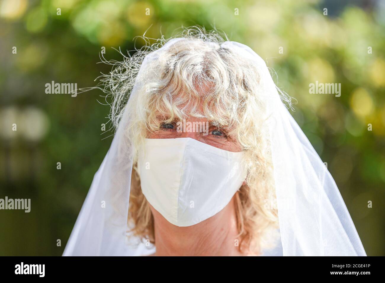Reife Frau weiblich trägt ihre alte Hochzeit Schleier und ein Gesichtsmaske während der Coronavirus COVID-19 Pandemie Stockfoto
