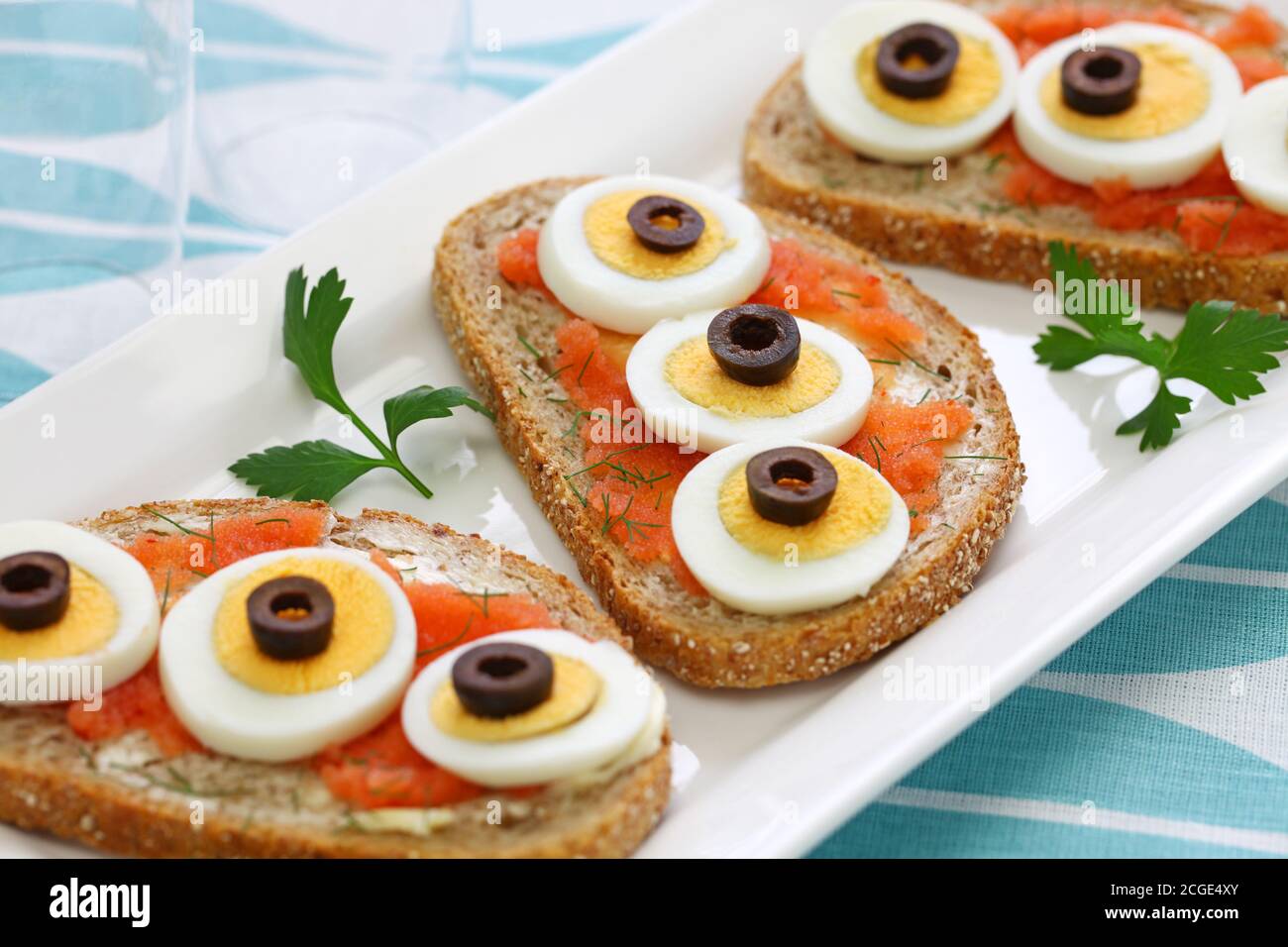 Swedish Open Sandwich mit in Scheiben geschnittenem gekochtem Ei, schwarzen Oliven und Dill auf gewürztem Kabeljau Roggenbrot. Stockfoto
