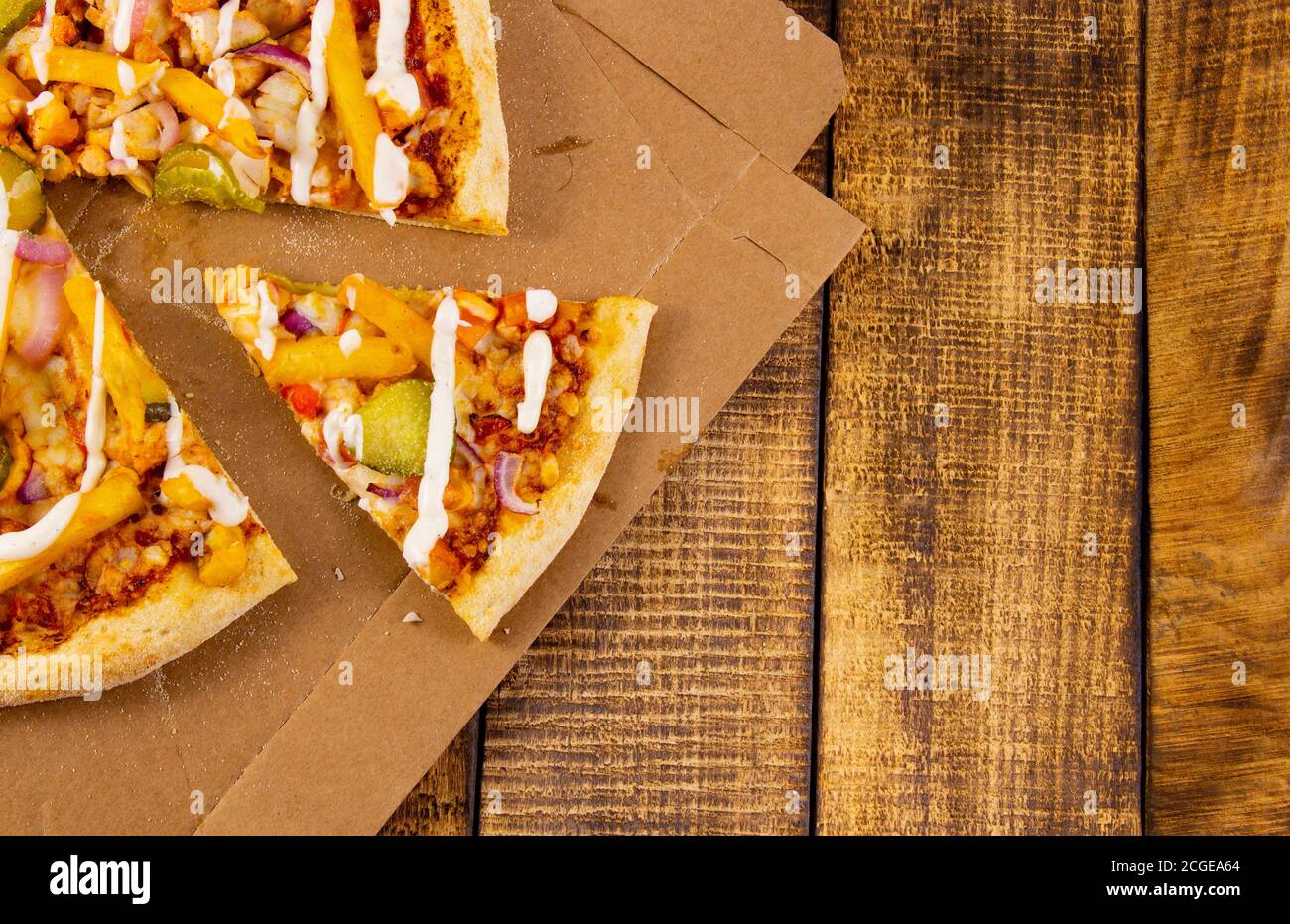 Pizza in Scheiben auf einem Holztisch in Nahaufnahme auf einer Pappschachtel. Stockfoto