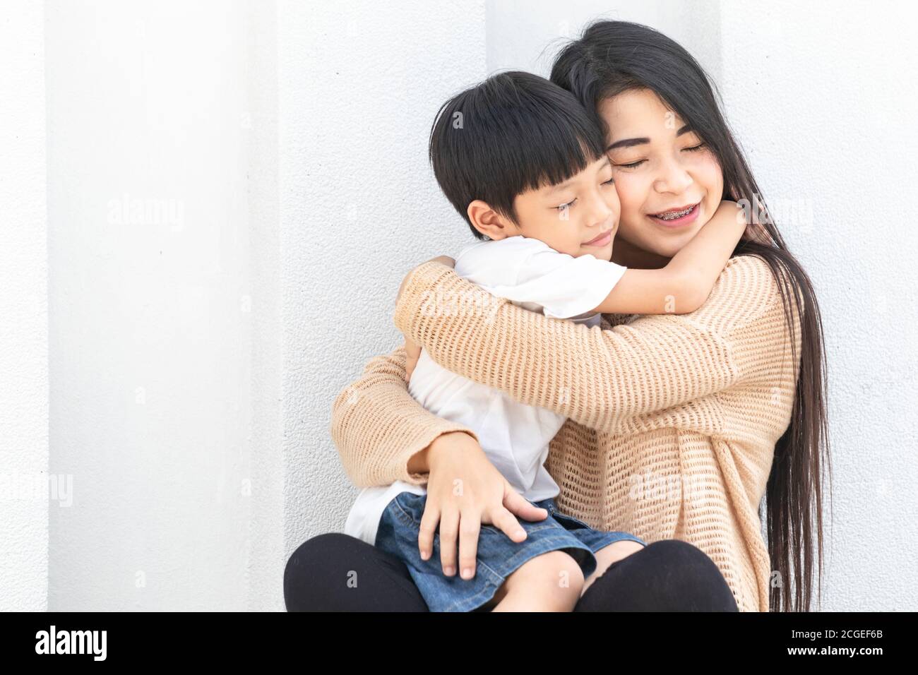 Portrait schöne Mutter und Kind glücklich umarmt. Asiatische Familie Mutter und Kind umarmen und schließen ihre Augen, niedlich und warm. Stockfoto