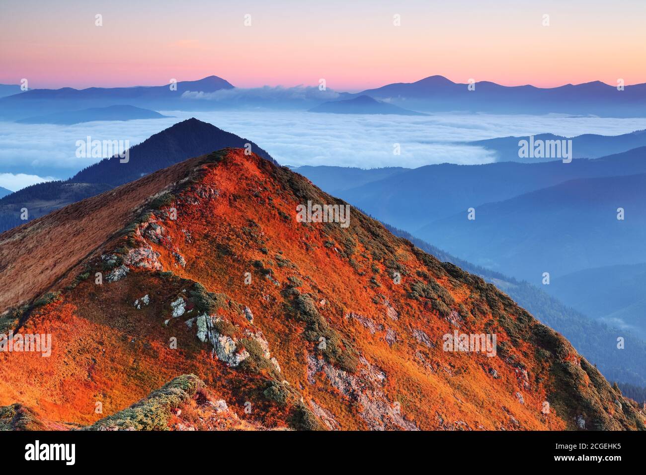 Sonnenaufgang. Herbstmorgen. Herbstszene. Landschaft mit hohen Bergen. Panoramablick. Natürliche Landschaft. Der Rasen mit orangefarbenem Gras. Herbsttapete Stockfoto