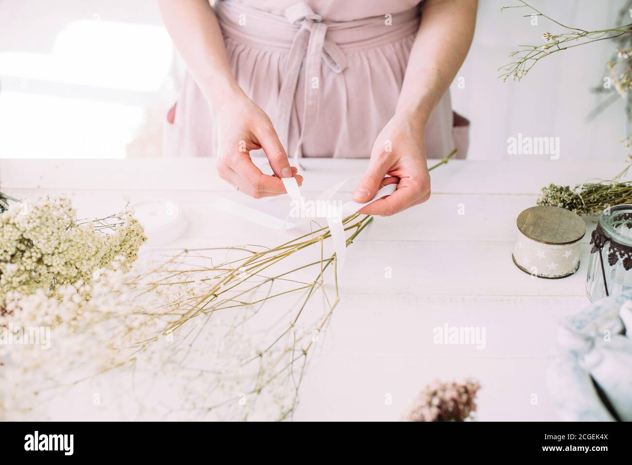 Hände einer Floristin Frau bei der Arbeit. Trockene Kompositionen und Blumensträuße für den Innenraum. Weiße Holz rustikalen Hintergrund. Stockfoto