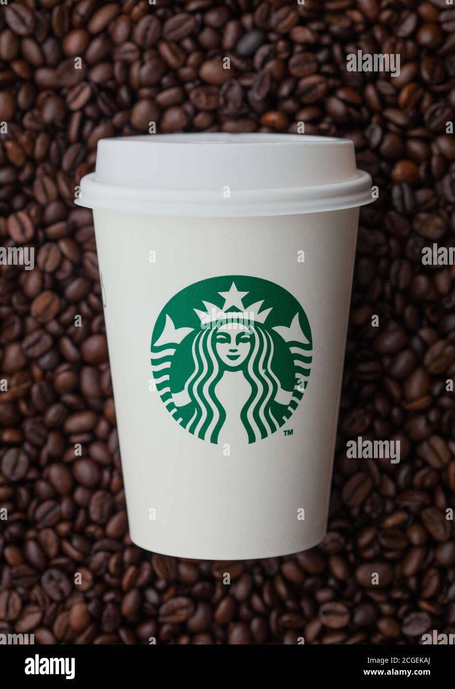 LONDON, Großbritannien - 09. SEPTEMBER 2020: Papiertasse zum Mitnehmen von Starbucks-Kaffee auf frischen rohen Kaffeebohnen. Stockfoto