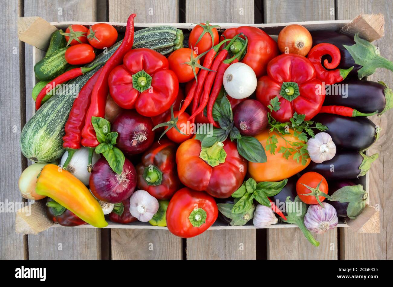 Ernte frisches Gemüse in einer Kiste auf einem Holzhintergrund, Draufsicht. Das Konzept der gesunden Ernährung. Stockfoto