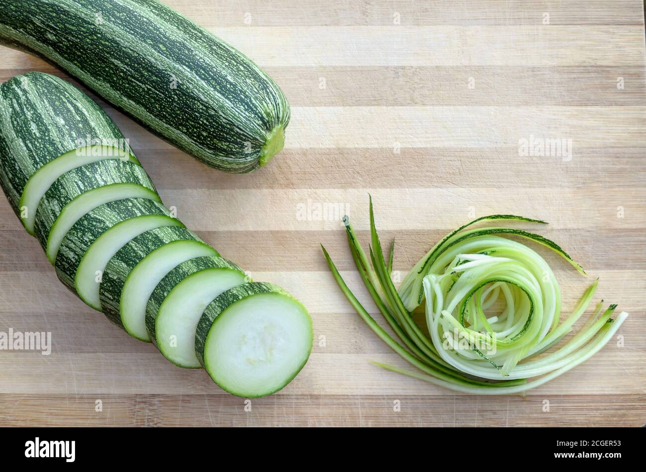 Roh geschnittene Zucchini auf einem Schneidebrett. Nahaufnahme, flach liegend Stockfoto