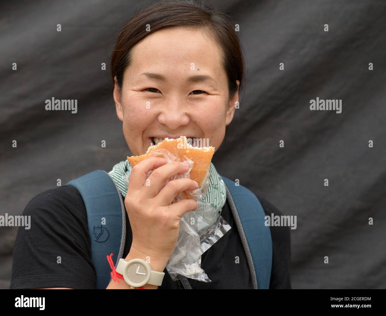 Weibliche japanische Tourist isst ein Brötchen und lächelt für die Kamera. Stockfoto