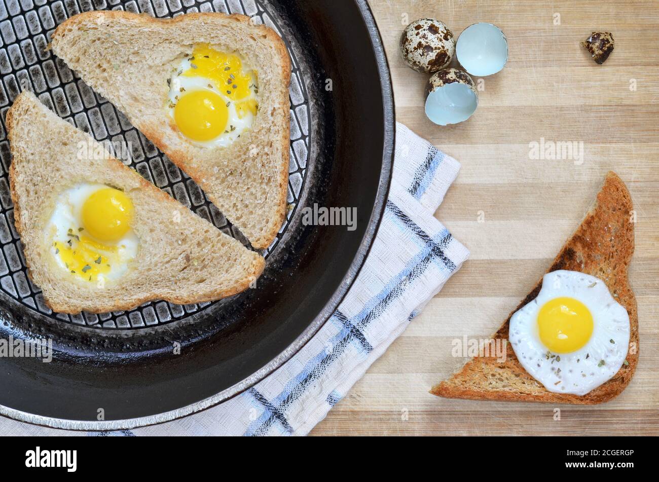 Brotscheiben mit gebratenen Wachteleiern in einer Bratpfanne auf einem hölzernen Schneidebrett als Hintergrund platziert, Draufsicht. Gesunde Ernährung Konzept. Stockfoto