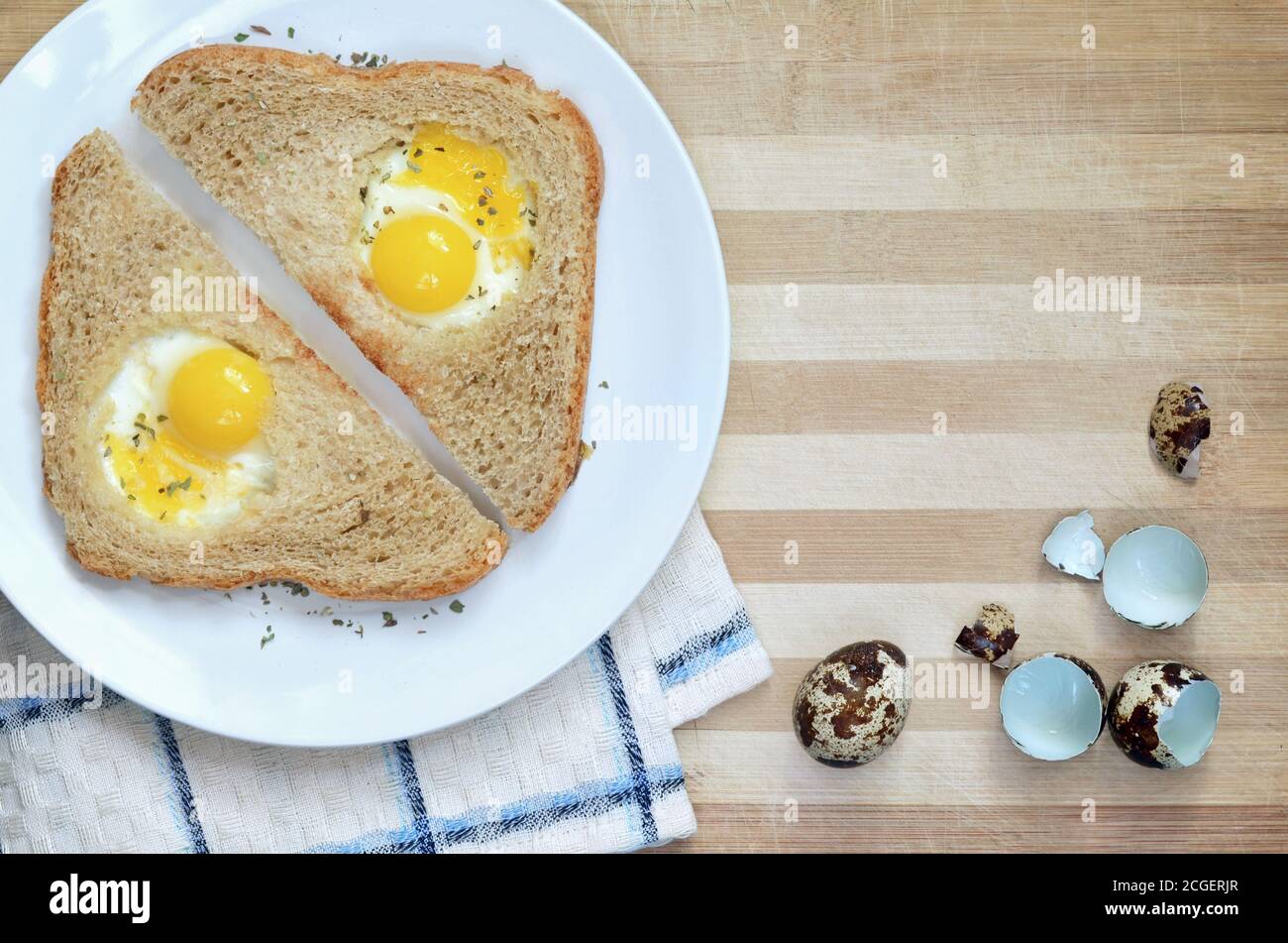 Sandwiches mit gebratenen Wachteleiern auf einem weißen Teller auf einem hölzernen Schneidebrett mit einem Küchentuch und Eierschalen, Draufsicht mit Kopierplatz. Stockfoto