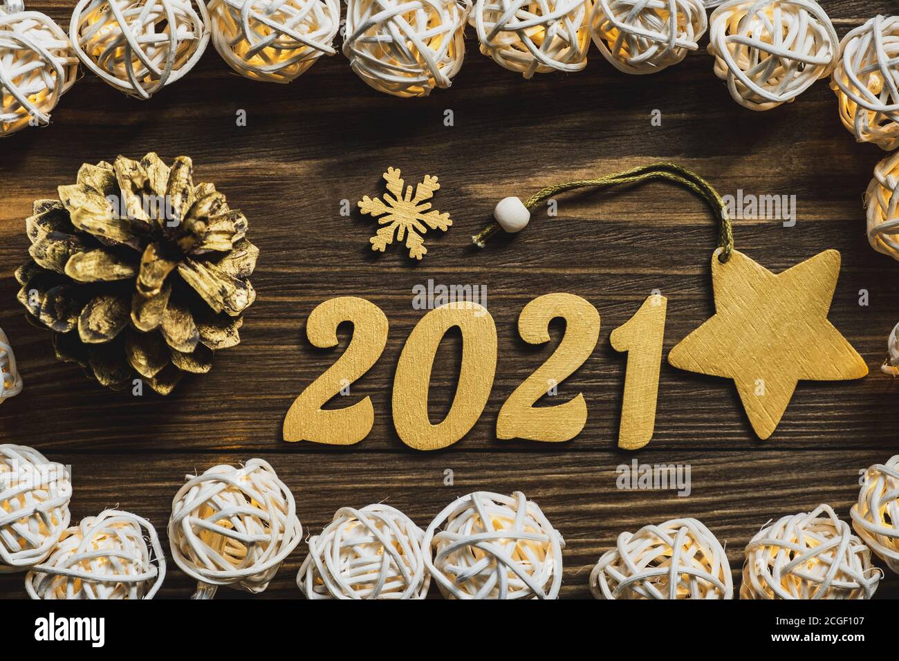 Neujahr 2021. Goldene Zahlen, Dekorationen und eine leuchtende Girlande auf einem dunklen Holztisch. Frohe Weihnachten und Frohes neues Jahr. Nahaufnahme. Draufsicht. Stockfoto