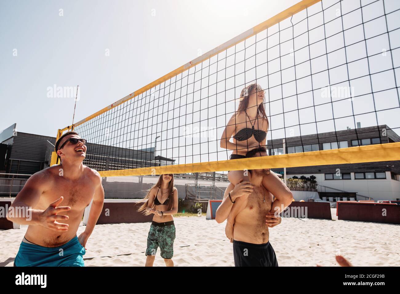 Menschen im Urlaub spielen Beachvolleyball Sport. Junge sportliche und positive Männer und Frauen Spaß Freizeit Volleyball Spiel im Sommer Wohn Stockfoto