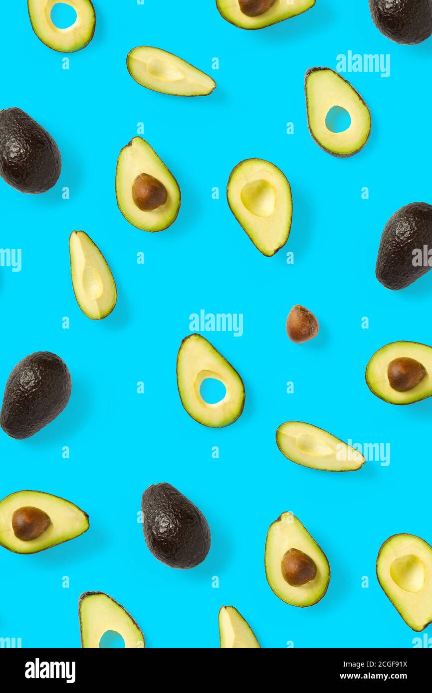 Avocado. Hintergrund aus isolierten Avocado-Stücken auf blauem Hintergrund. Flache Laie aus frischen reifen Avocados und Avacadostücken. Stockfoto