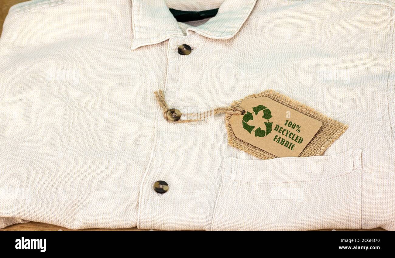 Symbol für Recycling-Kleidung auf dem Etikett mit Text aus 100 % recyceltem Stoff. Nachhaltige Mode und ethisches Shopping bewusstes Konsumdenken Stockfoto
