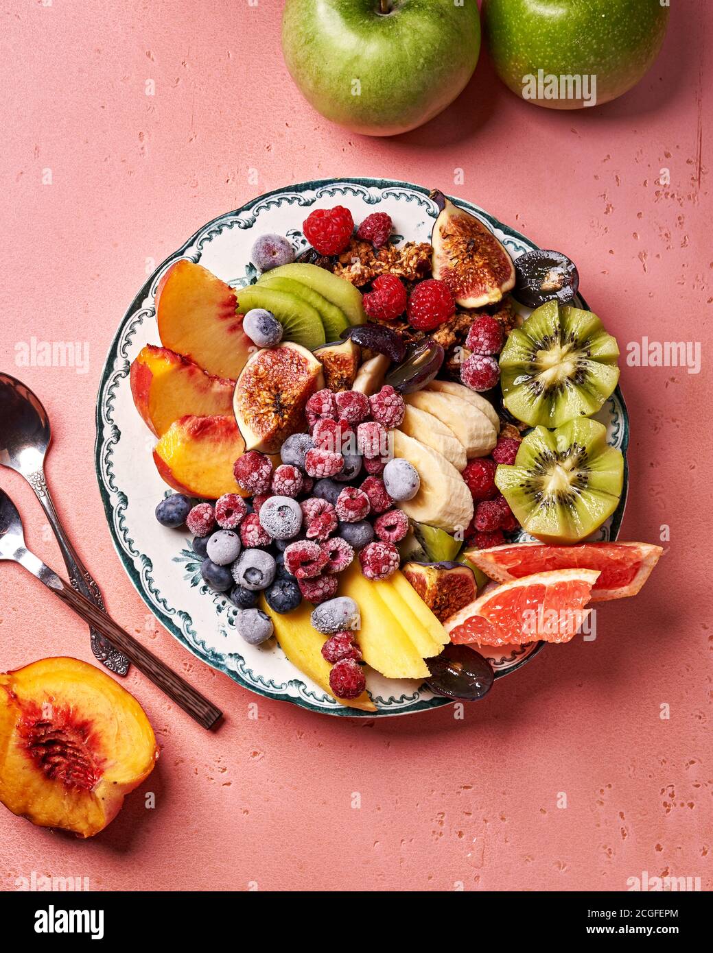 Verschiedene geschnittene Früchte auf Vintage-Teller. Draufsicht auf Mango, Kiwi-Früchte, Feigen, Trauben, Bananen, grüne Äpfel, Pfirsichfrüchte, Himbeeren und Heidelbeeren Stockfoto