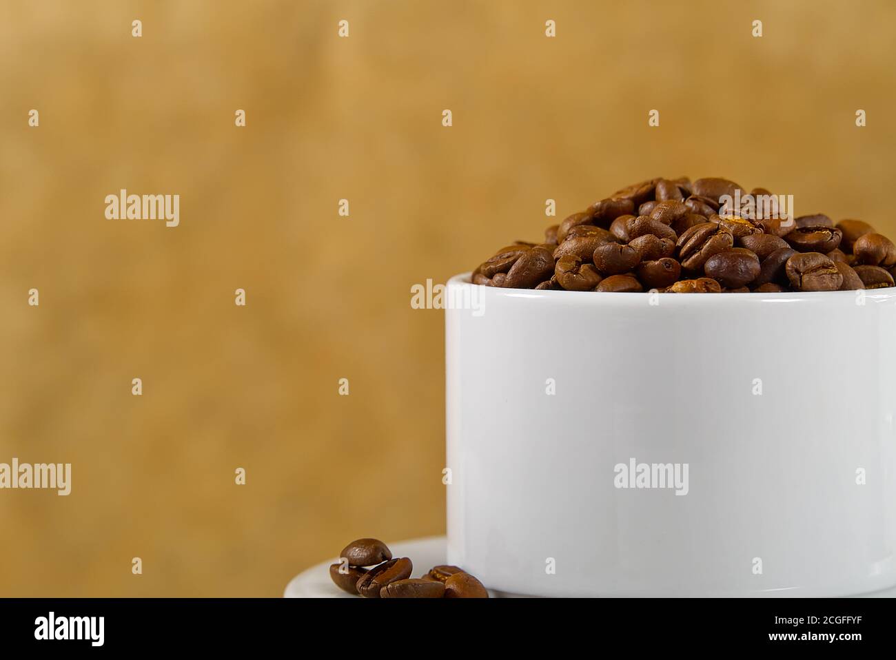 Internationaler Tag des Kaffees Konzept. Nahaufnahme weiße Kaffeetasse voller Kaffeebohnen auf beigem Hintergrund. Stockfoto