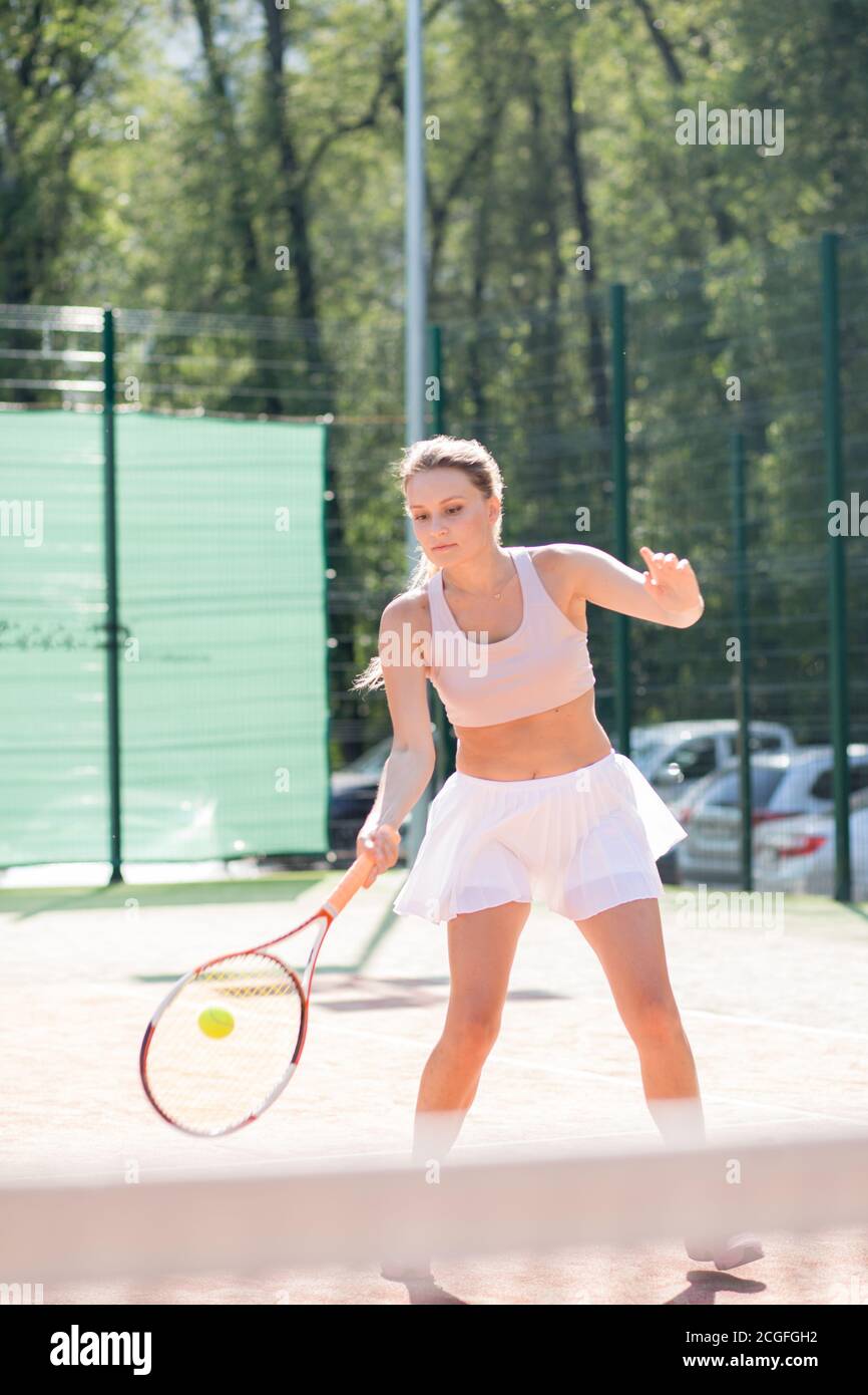 Fröhliche Frau im Tennis outfit Ausübung im Freien serviert, im Sommer morgen beginnt mit Tennis Training Stockfoto