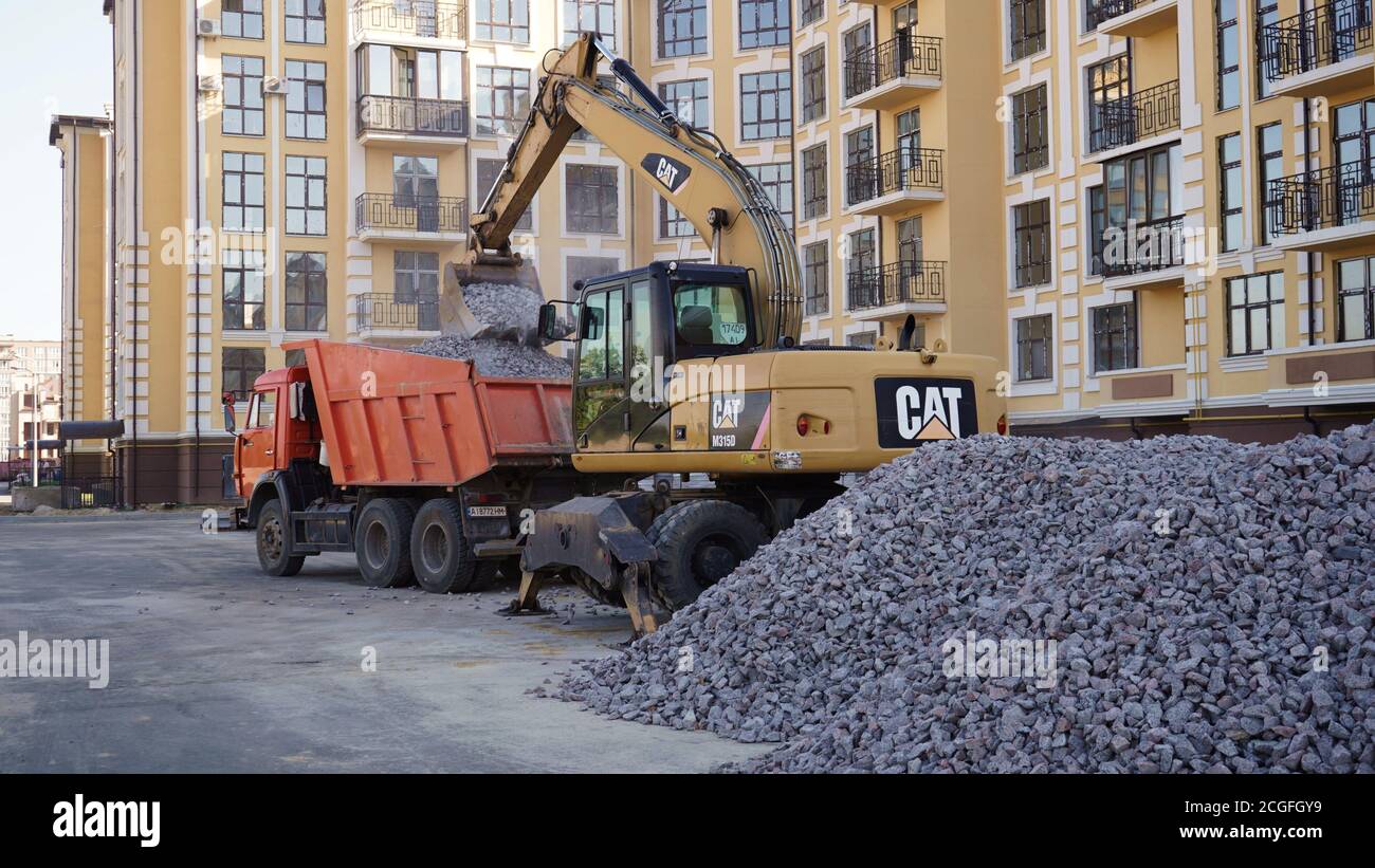 Yellow CAT Baggerlader arbeitet auf einer Baustelle mit Kies. Beladung von Kies auf einen LKW. Straßenbaustelle. Bau eines Parkplatzes l Stockfoto