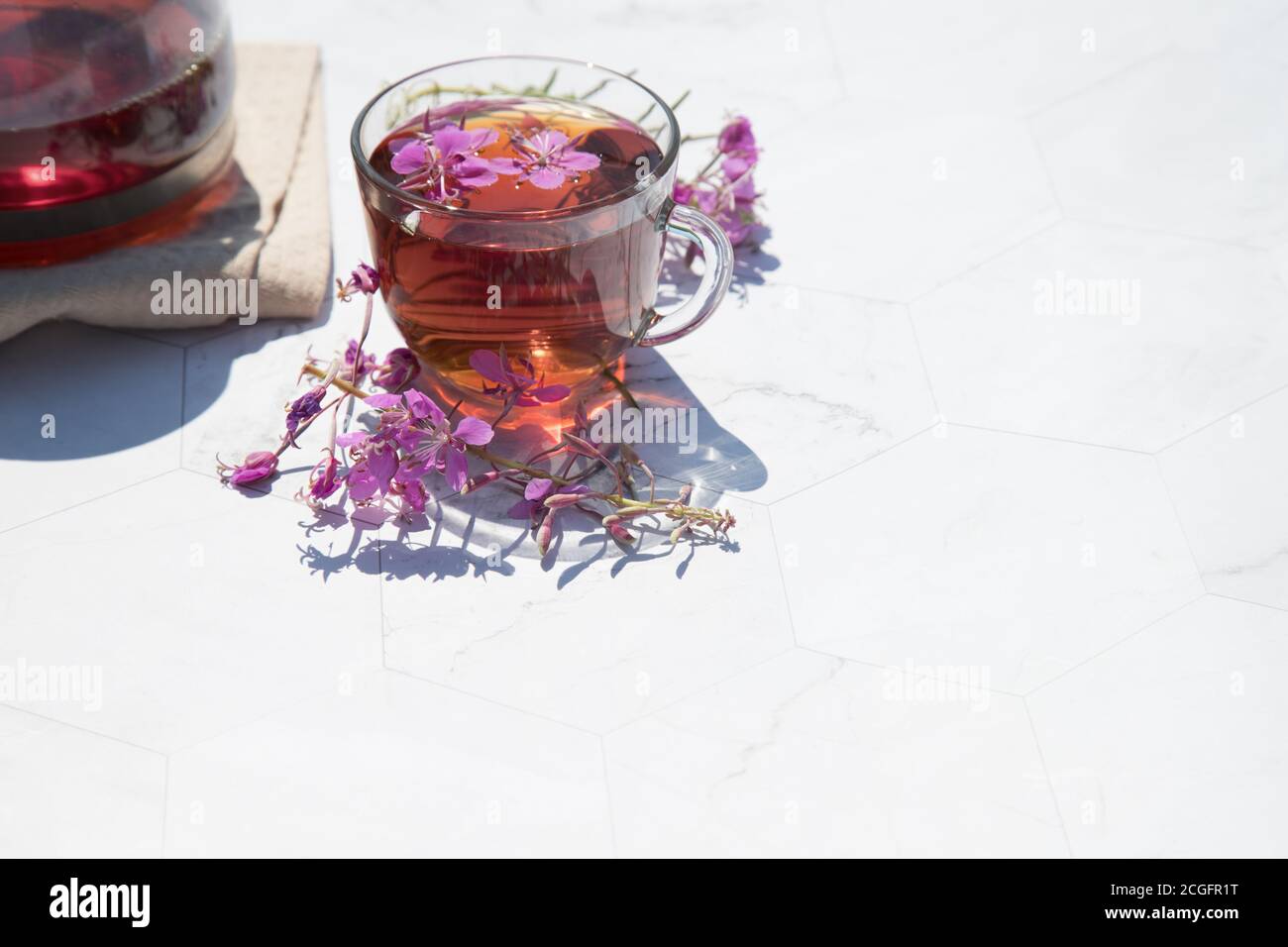 Kräutertee aus fermentierten Kipreya-Blättern in einem Glas Tasse auf einem hellen Hintergrund steht eine Teekanne mit Tee daneben.Traditioneller russischer Kopor-Tee (Ivan Stockfoto