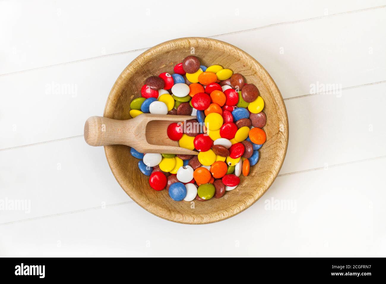 Bunte Hartschalenschokolade Bonbons in einer Holzschüssel auf Eine weiße Tabelle in der Draufsicht Stockfoto