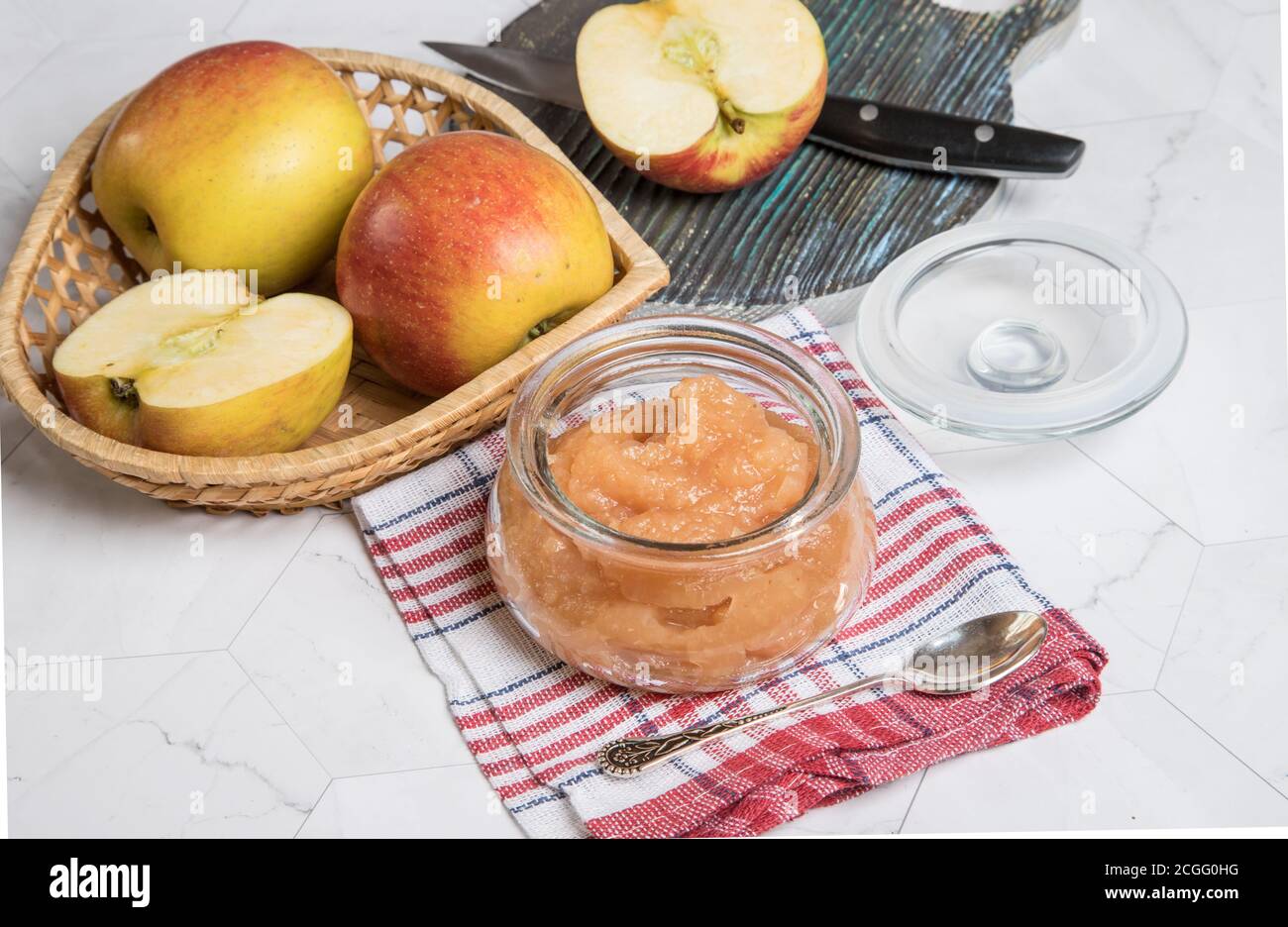 Apfelmus im Glas und frische Äpfel auf hellem Hintergrund. Nahaufnahme. Horizontale Ausrichtung. Stockfoto