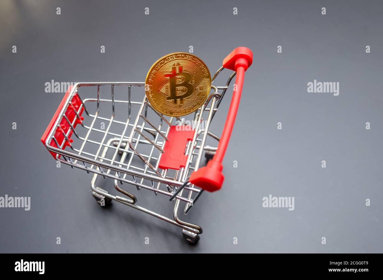 Goldbitcoin in einem roten Warenkorb auf schwarzem Hintergrund. Geschäftskonzept Stockfoto